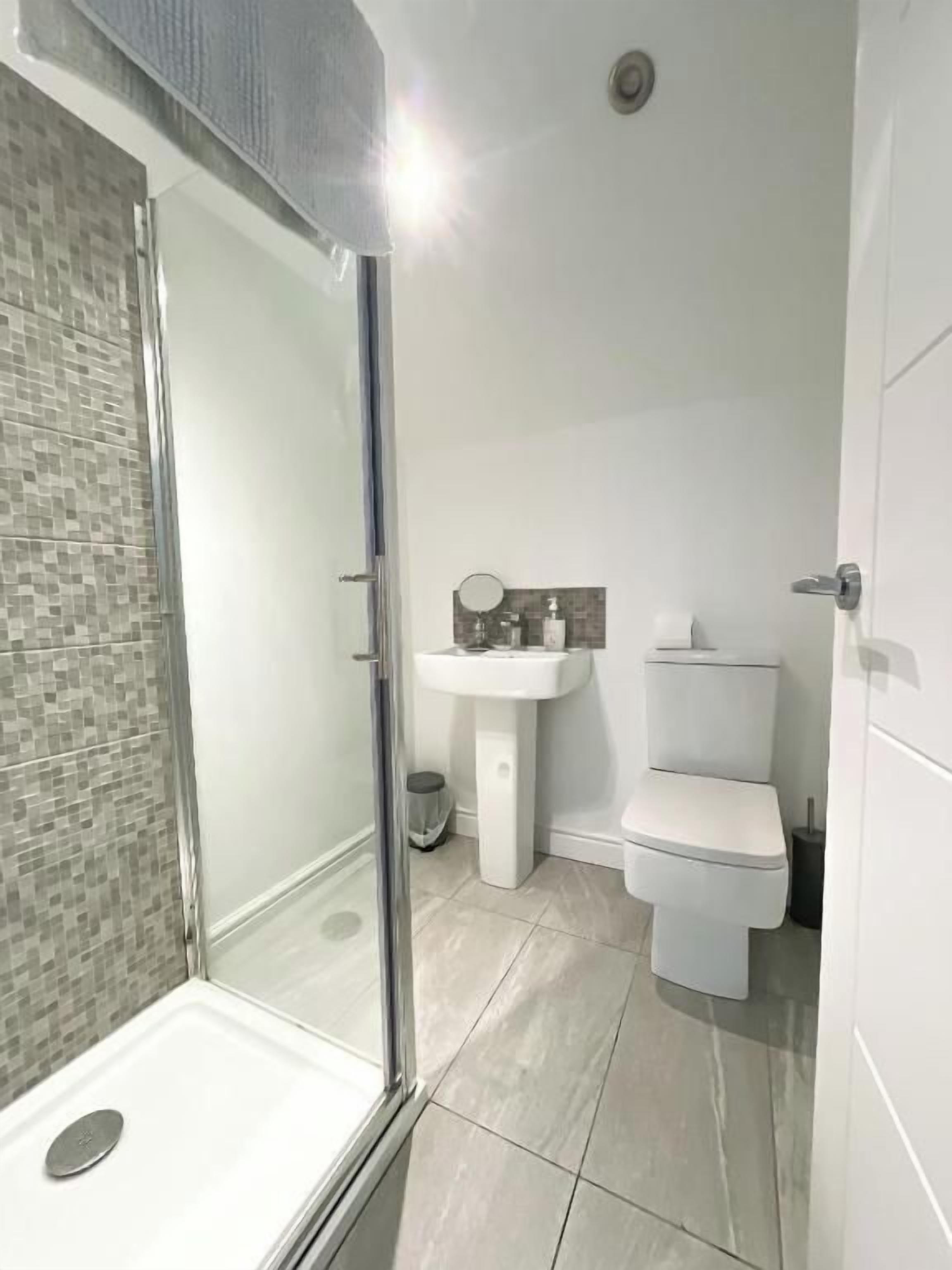 Une salle de bain avec une douche à parois de verre, un lavabo blanc et des toilettes.