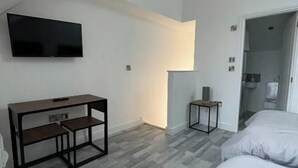 Una camera da letto con soffitto spiovente, un letto, una TV a parete e un piccolo tavolino.