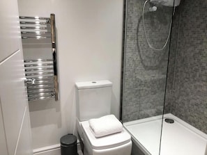 Ein modernes Badezimmer mit Toilette, Dusche und Handtuchhalter.