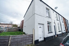 A residential building with a white exterior, a satellite dish, and a visible door. - Hyde Home | Stockport & Manchester Links | Parking (Greater Manchester)