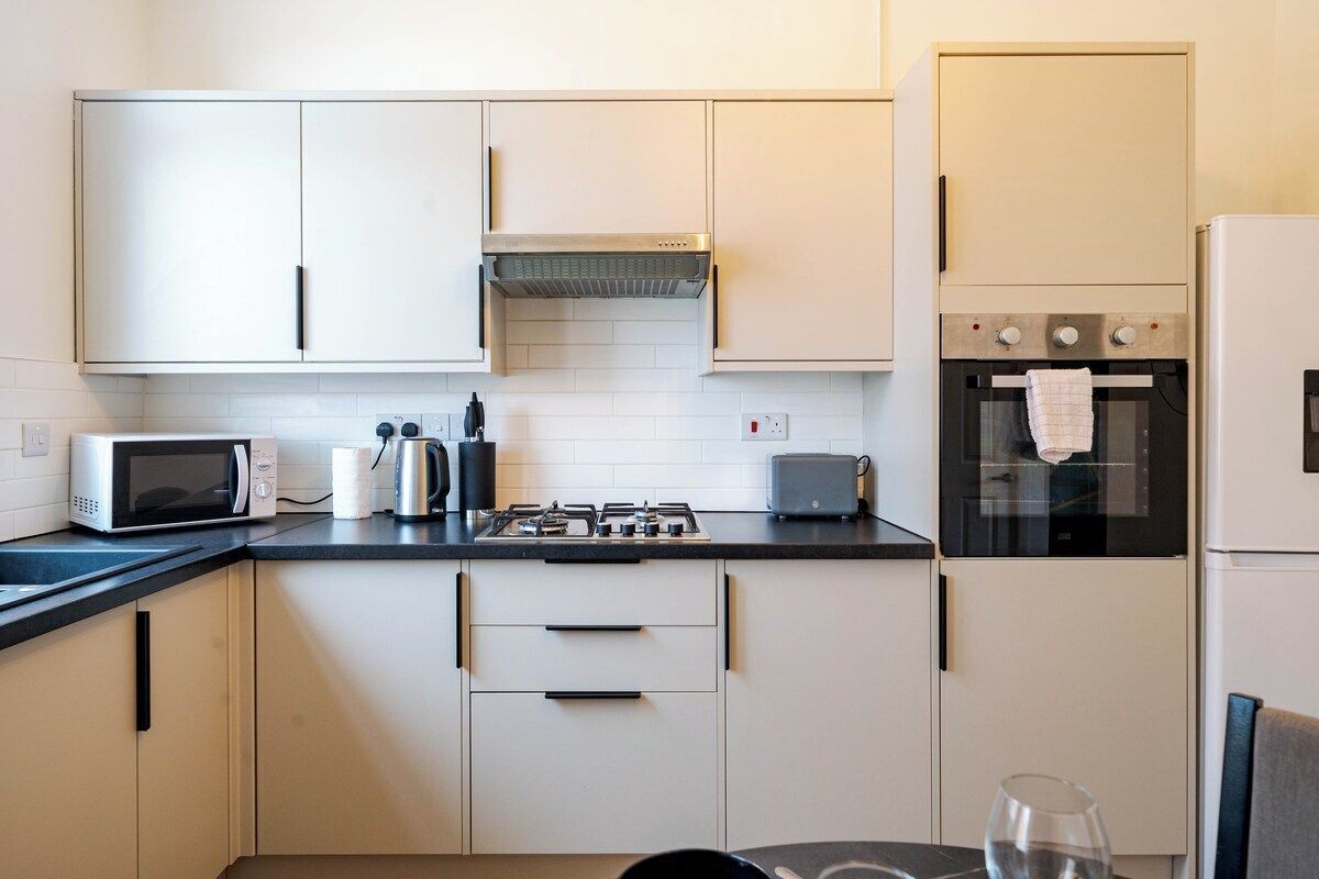 A modern kitchen with white cabinets, a microwave, a gas stove, a toaster, and a built-in oven.