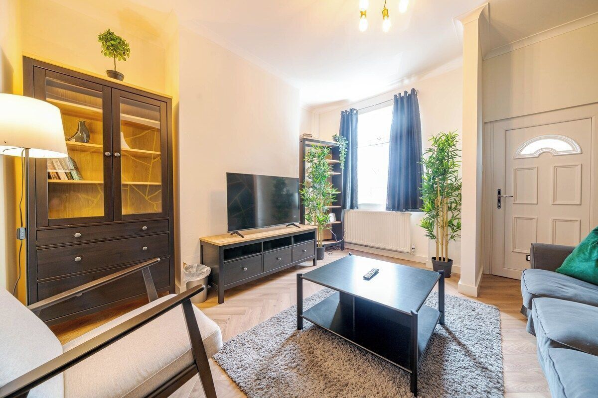 A living room with a flat-screen TV, a dark wooden cabinet, a grey sofa, and a coffee table.