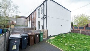 Un quartier résidentiel avec un bâtiment blanc, une clôture en bois et une cour gazonnée.