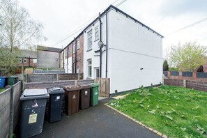 A residential area with a white building, a wooden fence, and a grassy yard. - Hyde Home | Stockport & Manchester Links | Parking (Greater Manchester)