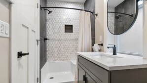 Un bany modern amb dutxa, un lavabo i un mirall.