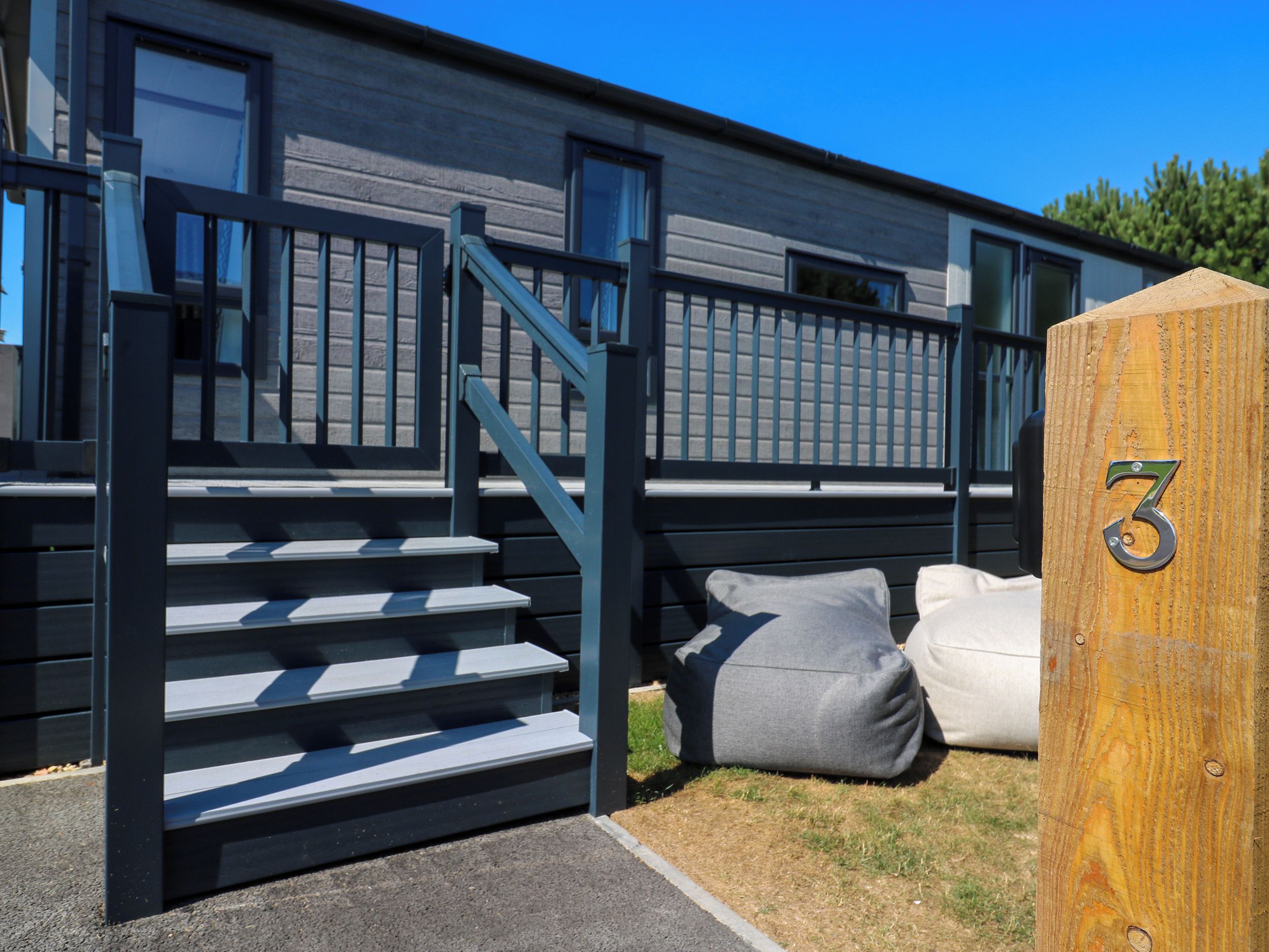 A set of outdoor stairs leading to a building with a number '3' sign, a bench, and a cushion.