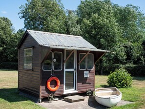A small wooden structure with a metal roof, a bicycle storage sign, and a tire hanging on the side.