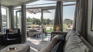 Un salon moderne avec un canapé, un fauteuil et une table. Une porte vitrée donne accès à un patio extérieur.