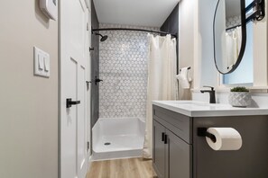 Ein modernes Badezimmer mit Dusche, Toilette und Waschbecken inklusive Spiegel.