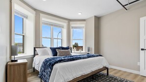 Ein Schlafzimmer mit einem Bett, Nachttischen, einem Fenster und einem gemusterten Teppich.