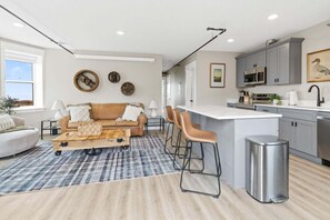 A modern kitchen with a bar area, a dining table with chairs, and a sofa in a living area. - Historic Brownstone Apartment, Heirloom Vacations (Duluth)