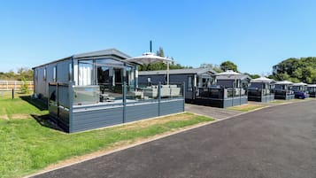 A row of mobile homes with outdoor seating areas and a hot tub.