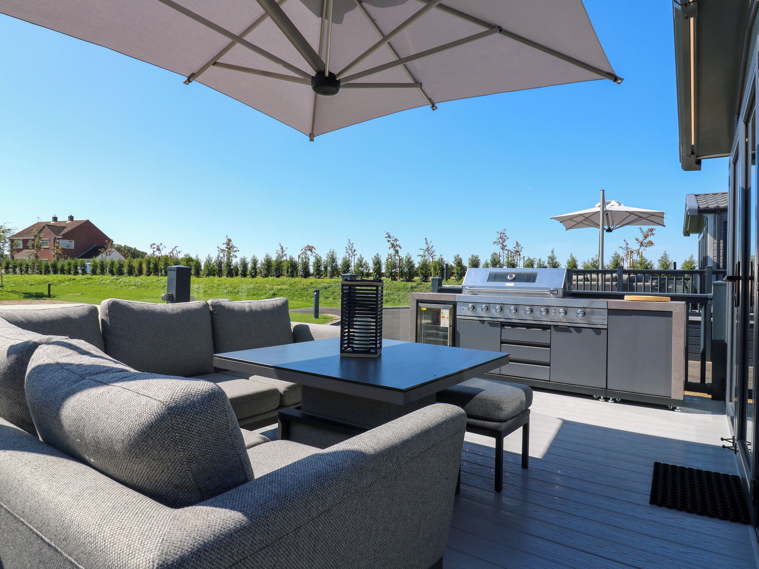 An outdoor patio with a grill, seating, and umbrellas.