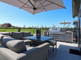 Un patio al aire libre con una parrilla, asientos y sombrillas.