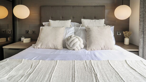 A modern bedroom with a large bed, two bedside tables, and a headboard.
