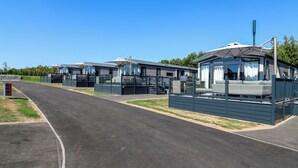 A row of modern, single-story mobile homes with large windows and a covered outdoor seating area.