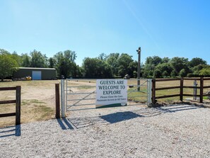 A gravel area with a metal gate and a sign welcoming guests to explore. - Lakewood Plot 2 (Clacton-on-Sea)