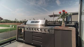 Una cocina exterior con una parrilla de acero inoxidable, un horno empotrado y un lavamanos.