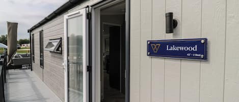 Ein Gebäude mit Schiebetür-Eingang, einem Schild mit der Aufschrift 'Lakewood 42' - 2 Schlafzimmer, und einer kleinen Außen-Sitzgelegenheit.