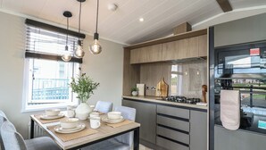 Una cocina moderna con comedor, que incluye una mesa de madera, sillas grises e iluminación colgante.