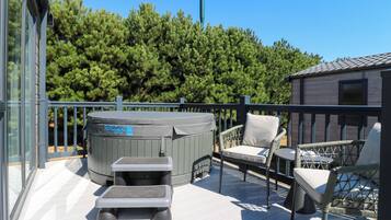 Una terraza con mobiliario exterior, un jacuzzi y vistas a un bosque.