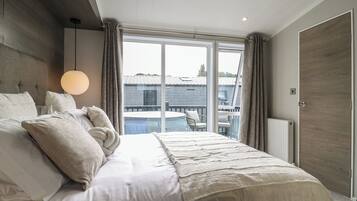 Un dormitorio con una cama grande, vistas a una piscina y una puerta de madera.