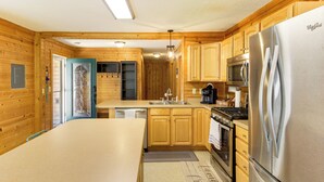 A compact kitchen with wooden cabinets, a stainless steel refrigerator, a microwave, and a stove.