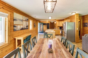 Interior de madera con una mesa de comedor, sillas, una zona de cocina y un refrigerador.