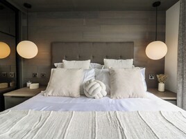 Un dormitorio moderno con una cama grande, dos mesitas de noche y un cabecero.