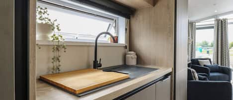 Una cocina moderna con encimera de madera, grifo negro y ventana sobre el lavamanos.