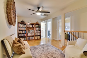 A spacious living room with a large bookshelf, a ceiling fan, and a staircase. - Three Springs Estate 7BR Retreat With Pond (Oregon City)