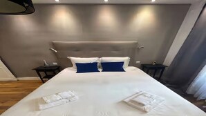 Ett hotellrum med en stor säng, två sängbord och en modern sänggavel.