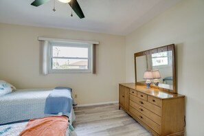 Ein Schlafzimmer mit Bett, Kommode, Spiegel und Fenster.