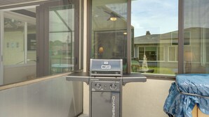 En grill med digitalt display, placeret nær et vindue med udsigt over et boligområde.