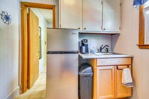Cocina compacta con refrigerador, cafetera y lavamanos.