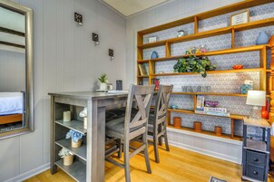 Una habitación con escritorio de madera, sillas, estantería y espejo.