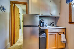 Cocina compacta con refrigerador, cafetera, pileta y basurero.
