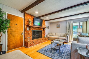 A living room with a brick fireplace, a television mounted above it, a sofa, and a coffee table.