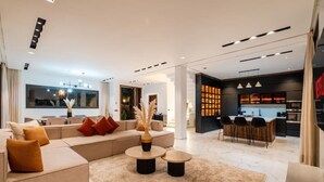 Ein modernes Wohnzimmer mit Sofa, Couchtisch und einem Essbereich mit Stühlen.