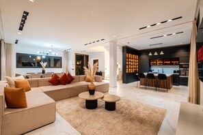 A modern living room with a sofa, coffee table, and a dining area with chairs. - Villa Vamo | Luxury 5-Bedroom Golf Villa with Heated Pool | Amelkis Marrakech (Marrakech)