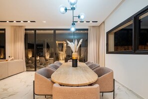 A modern dining area with a round table, cushioned chairs, and a decorative vase. - Villa Vamo | Luxury 5-Bedroom Golf Villa with Heated Pool | Amelkis Marrakech (Marrakech)