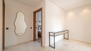 Ein Flur mit Marmorboden, einem Wandspiegel und einer Holztür, die zu einem Schlafzimmer führt.