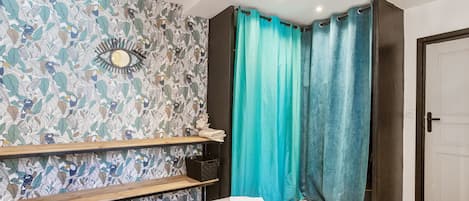 Ein Hotelzimmer mit einem Bett, einem Regal, einem Vorhang und einer Tür.