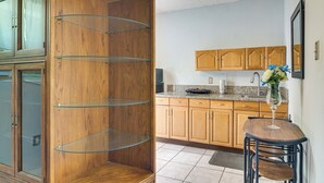 A kitchen with wooden cabinets, a granite countertop, and a glass shelving unit. - Gateway to Everglades! Extended Stay for Couples (Miami)