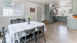 A modern kitchen with grey cabinets, a stainless steel refrigerator, and a dining area with a table and chairs. - City Limits in Historic Spearfish, South Dakota (Spearfish)