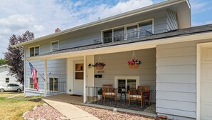A two-story house with a covered porch, a flag, and a car parked in the driveway. - City Limits in Historic Spearfish, South Dakota (Spearfish)
