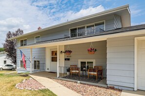 A two-story house with a covered porch, a flag, and a car parked in the driveway. - City Limits in Historic Spearfish, South Dakota (Spearfish)