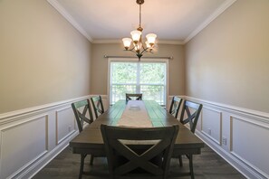A dining room with a long table, chairs, a chandelier, and a window with blinds. - 8 Mi to Fort Campbell! Family Home w/ Patio & Yard (Clarksville)