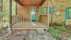 A wooden cabin with a porch, a door, and a small statue.