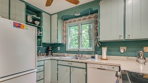 A kitchen with teal cabinets, a refrigerator, a sink, and a stove.
